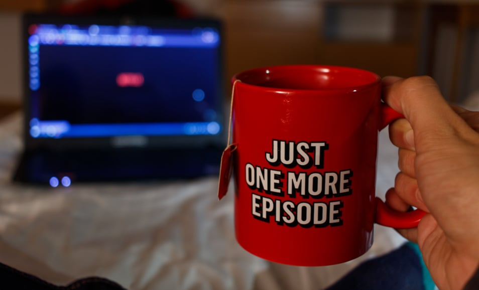 Man Watching series while holding with a cup of tea with streaming inspired inscription. Just one more episode. Quarantine concept